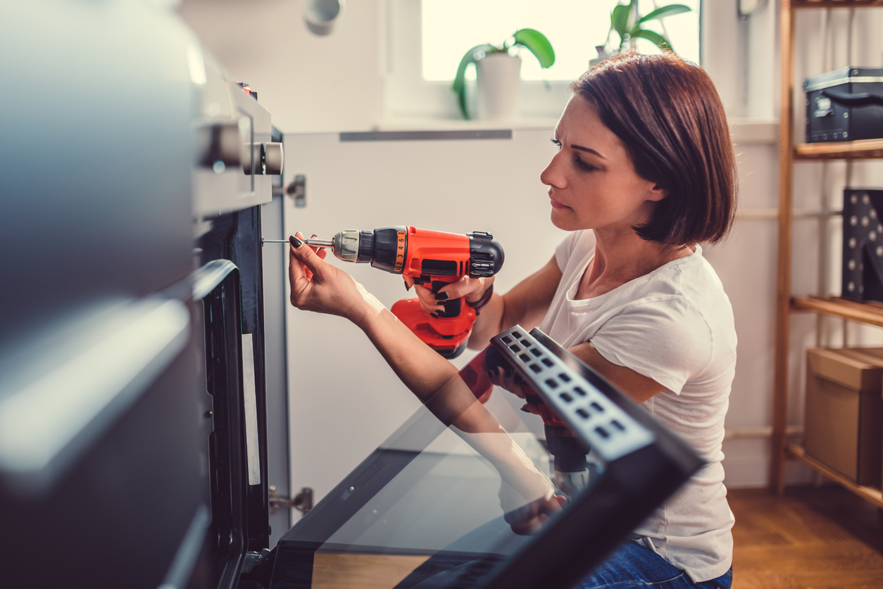 Woman fixing tenant damage with electric drill