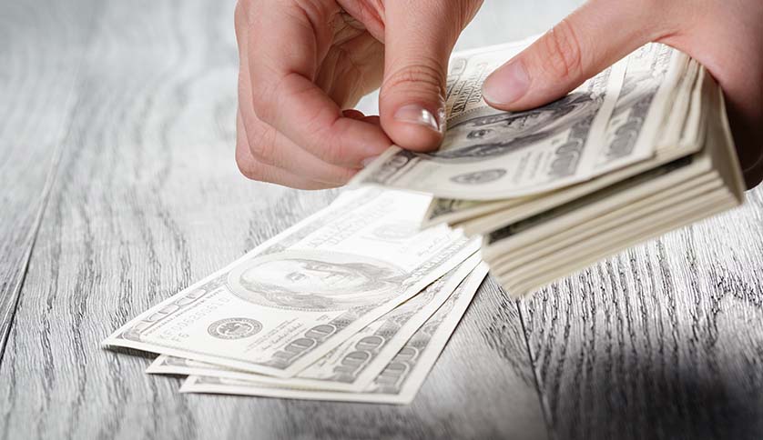 young female hands count dollar bills on wood table