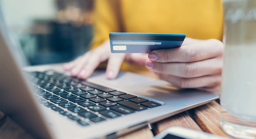 Person holding a credit card making vendor payments on a computer