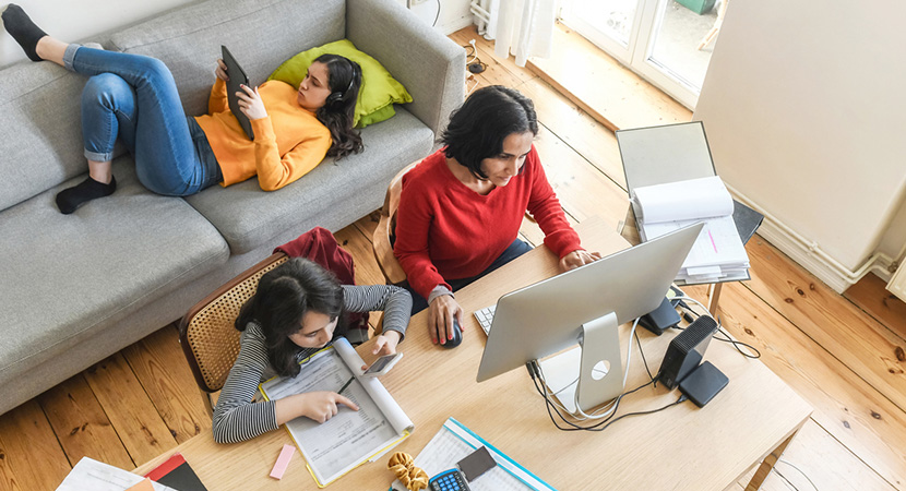 A mother working from home while her children complete their homework next to her.