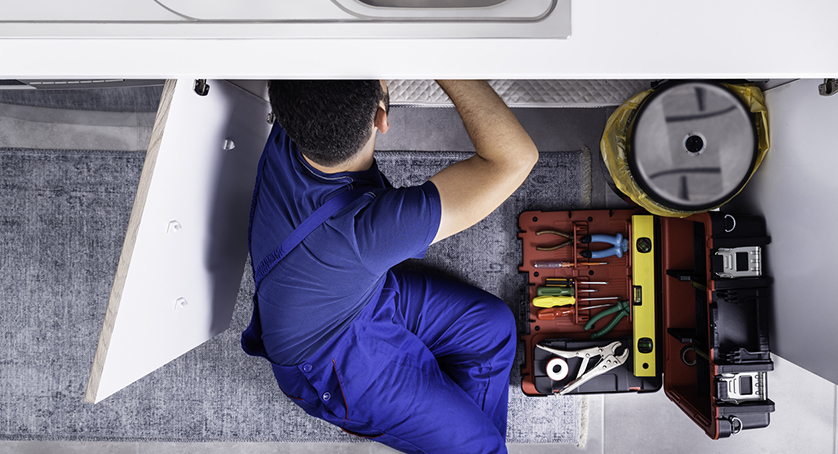 Plumber performing property maintenance on pipes