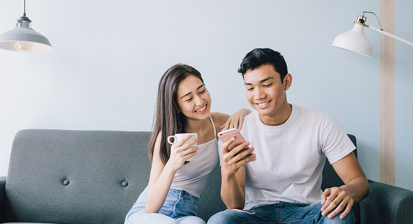 Young couple sitting on sofa smiling