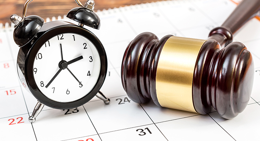 Judge's gavel with clock and calendar on the table.