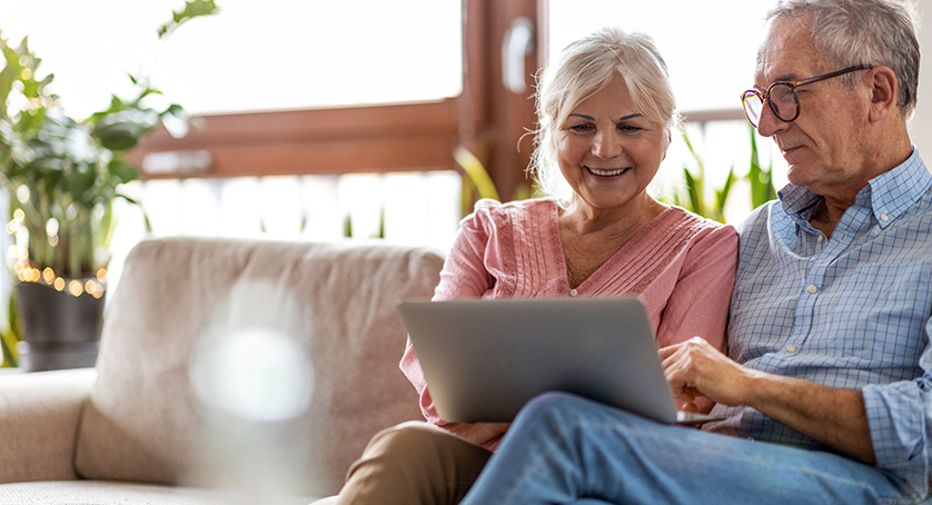 Mature couple using a laptop while relaxing at home