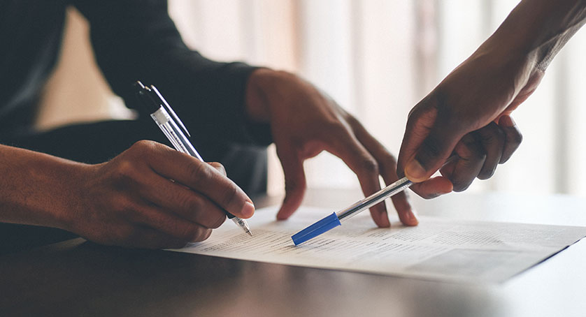 Cropped shot of an unrecognizable man filling a document with the help of a financial advisor at home