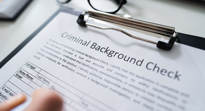 Close-up Of Human Hand Filling Criminal Background Check Application Form With Pen