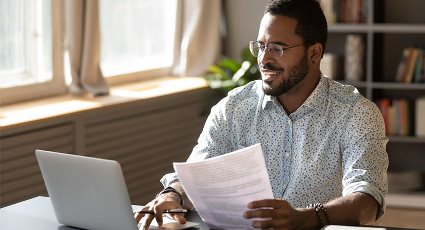 Man using a computer and holding a sheet of paper