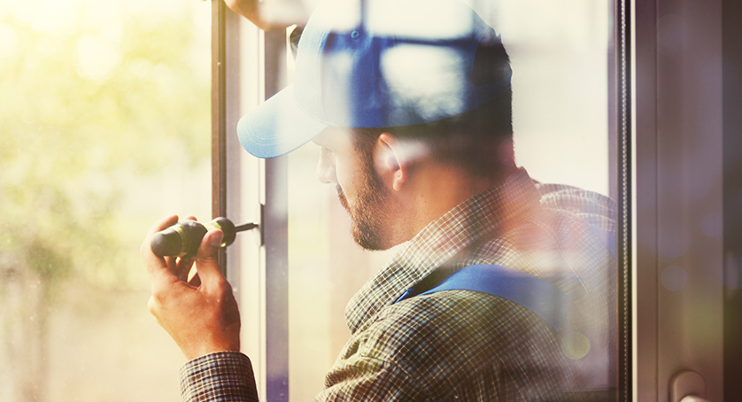 service man installing window with screwdriver