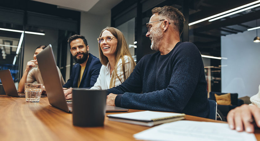 three people sitting in a board room, laughing