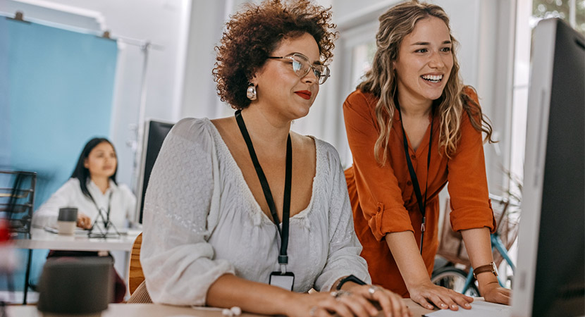 Two women using a computer in an office setting