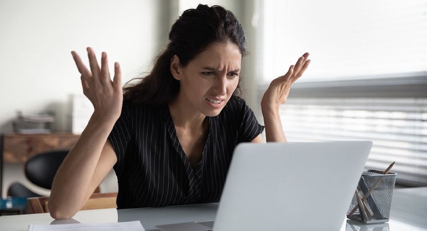 Woman looking frustrated at computer due to possible fraud