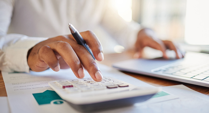 Person using calculator and computer to represent expense management